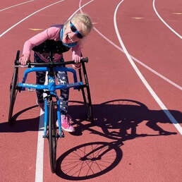 Photo of a smiling young girl on a running track with a RAD RaceRunner running frame