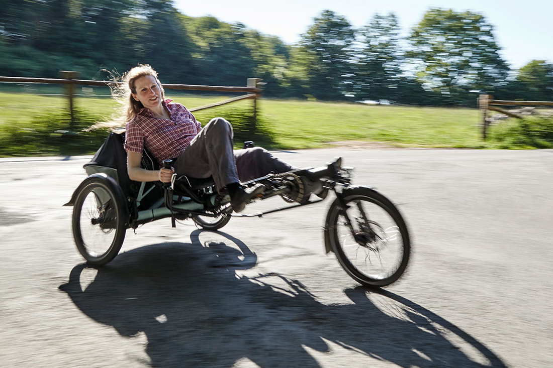 Woman riding a Hase EVO recumbent trike with e-motor