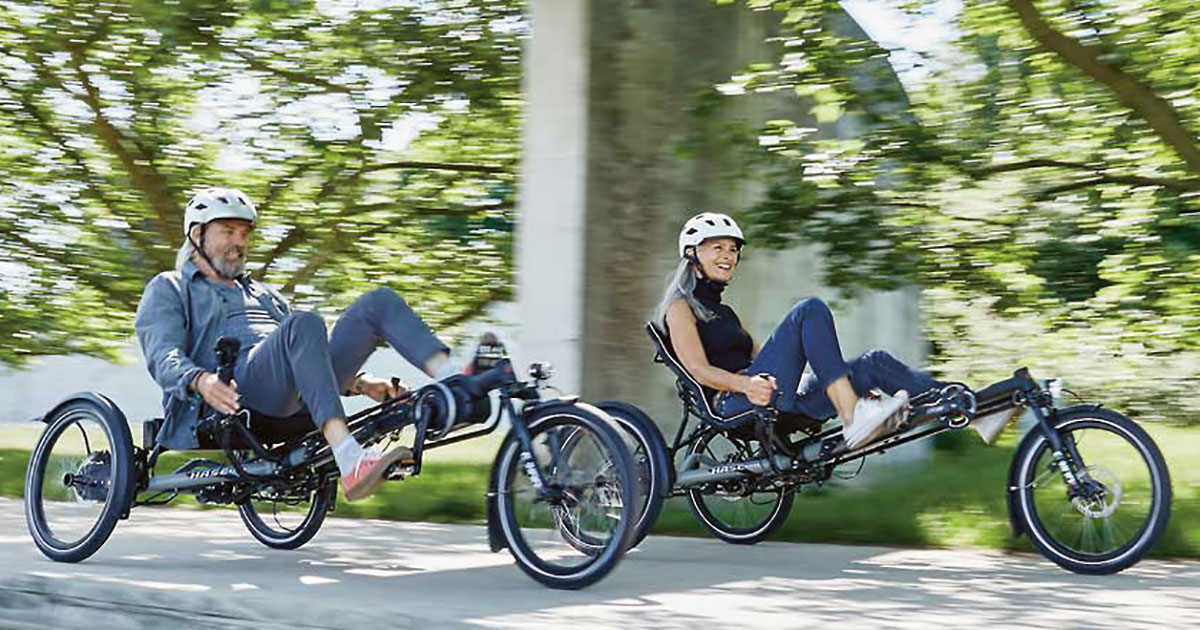 Two people riding Hase Kettwiesel EVO STEPS recumbent trikes