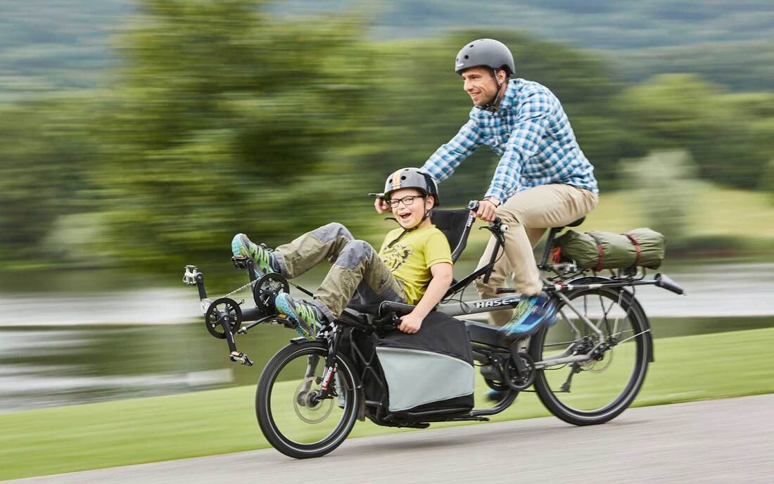 Man and boy riding an adapted Hase Pino tandem bike