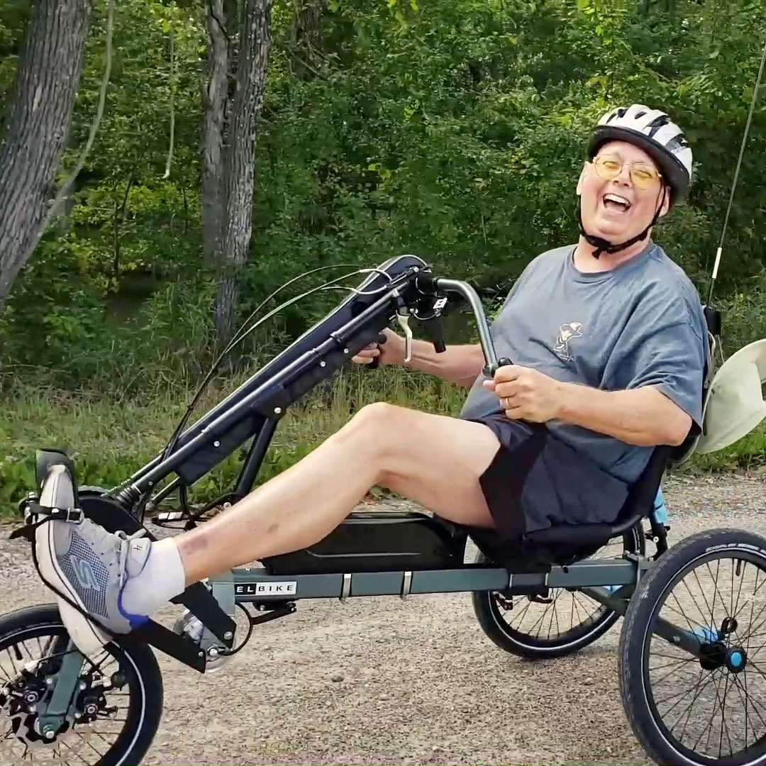 A smiling man riding a dual drive recumbent trike