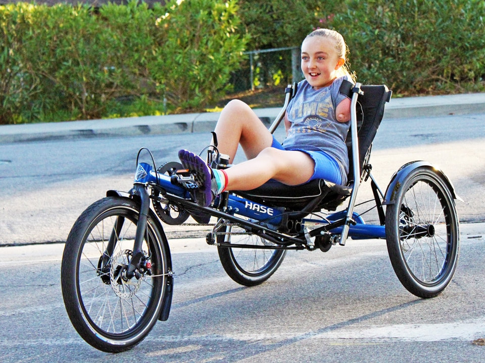 Emily riding her specially adapted recumbent trike with shoulder steering and foot shifting