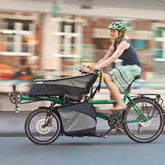 Woman riding a Hase Pino as a cargo bike with porter bags