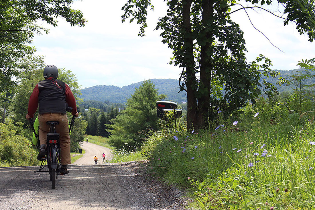 Couple riding a Hase Pino tandem bike on a dirt road in Vermont